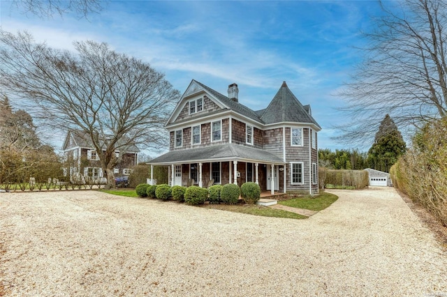 victorian house with covered porch, an outbuilding, and a garage