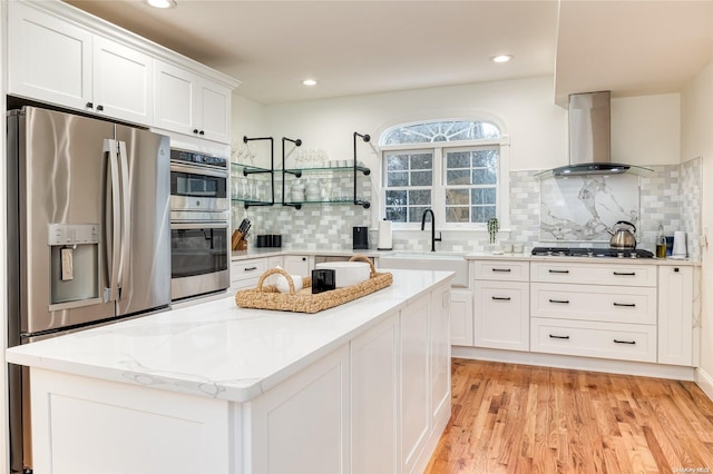 kitchen featuring light wood-type flooring, stainless steel appliances, sink, white cabinetry, and range hood