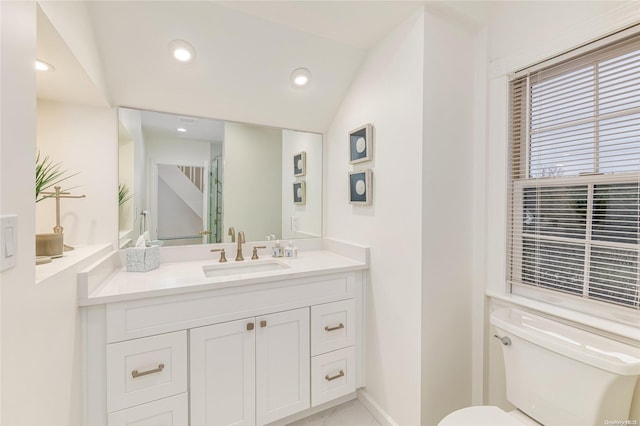 bathroom with vanity, vaulted ceiling, and toilet