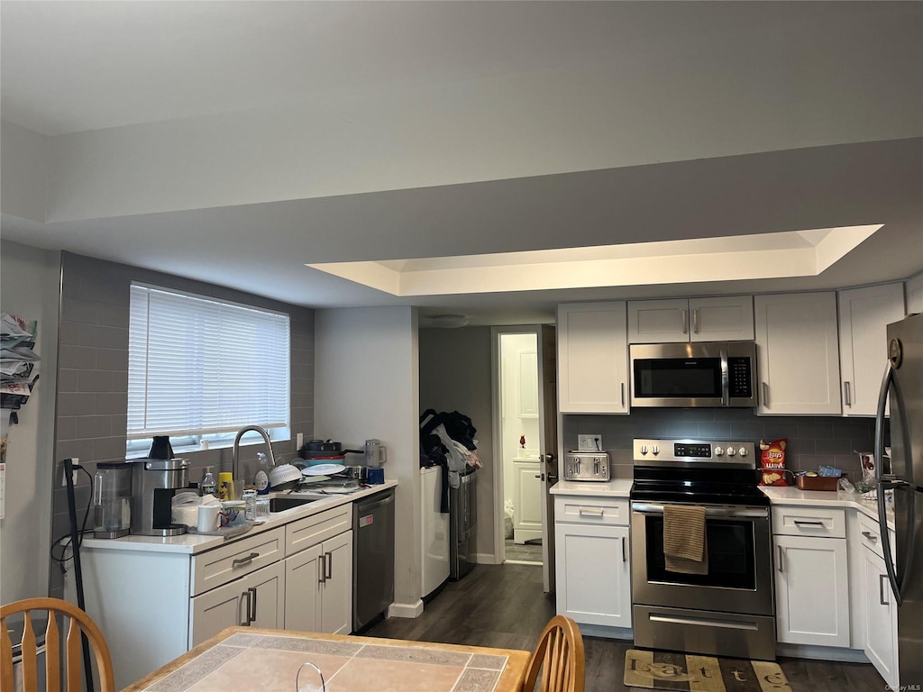 kitchen with black appliances, a tray ceiling, backsplash, and light countertops