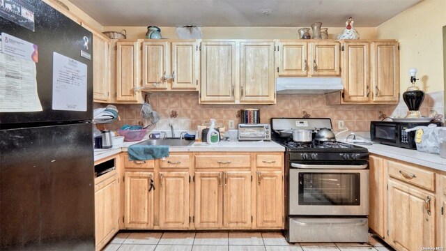 kitchen with black appliances, light tile patterned floors, sink, and light brown cabinetry