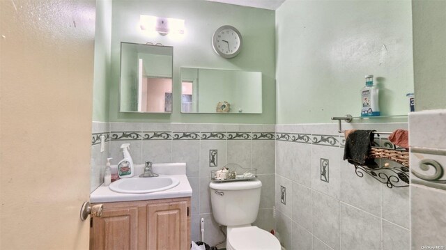 bathroom with vanity, toilet, and tile walls