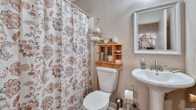 bathroom with a shower with shower curtain and toilet