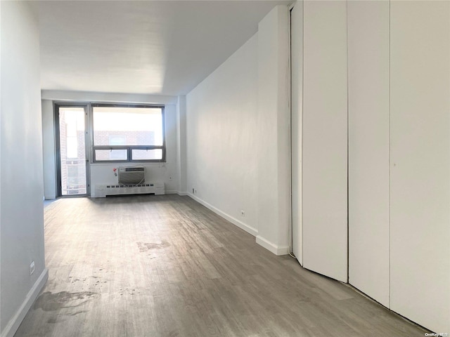 unfurnished living room featuring a baseboard radiator and light hardwood / wood-style flooring