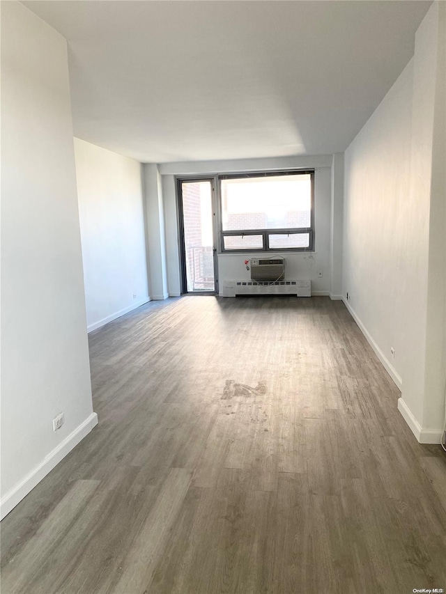 unfurnished living room with a wall mounted air conditioner and dark wood-type flooring