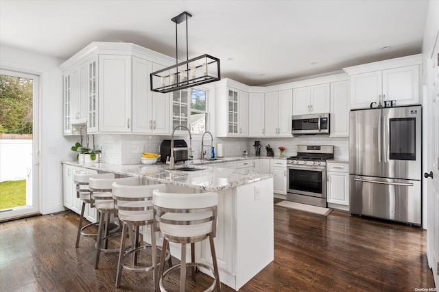 kitchen with decorative backsplash, dark hardwood / wood-style flooring, stainless steel appliances, decorative light fixtures, and white cabinetry