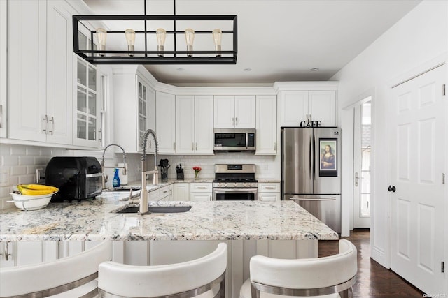 kitchen with kitchen peninsula, light stone counters, stainless steel appliances, white cabinets, and a breakfast bar area