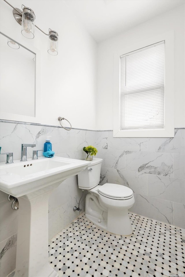 bathroom with tile patterned floors, toilet, tile walls, and sink