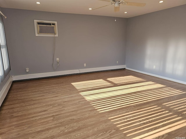 spare room featuring a wall mounted air conditioner, ceiling fan, wood-type flooring, and a baseboard heating unit