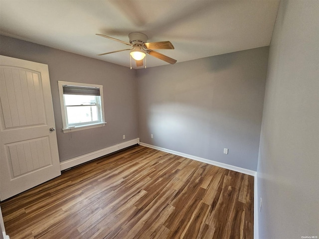 empty room featuring hardwood / wood-style flooring, ceiling fan, and a baseboard heating unit