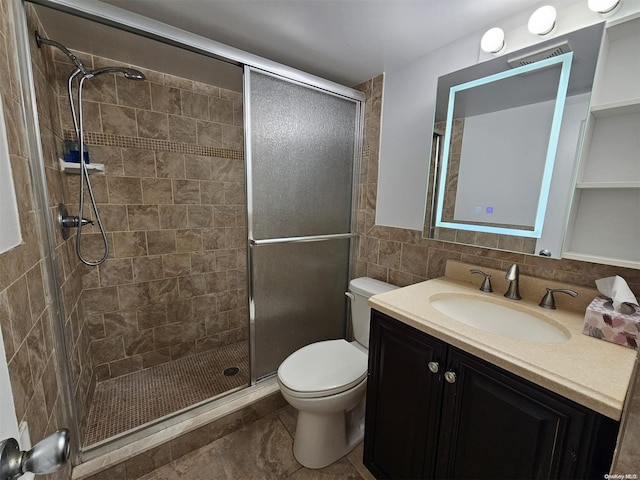 bathroom featuring vanity, tile patterned flooring, toilet, tile walls, and walk in shower