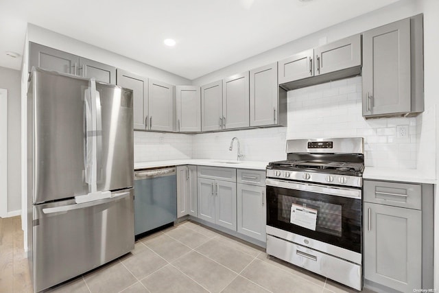 kitchen featuring decorative backsplash, stainless steel appliances, sink, gray cabinets, and light tile patterned flooring