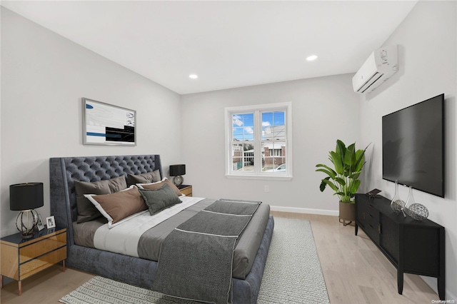 bedroom featuring light hardwood / wood-style floors and a wall unit AC