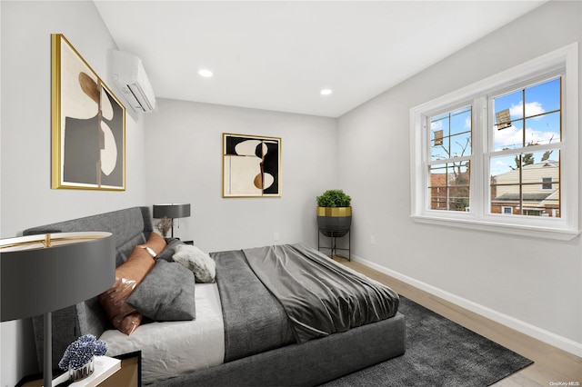 bedroom with a wall unit AC and light hardwood / wood-style floors