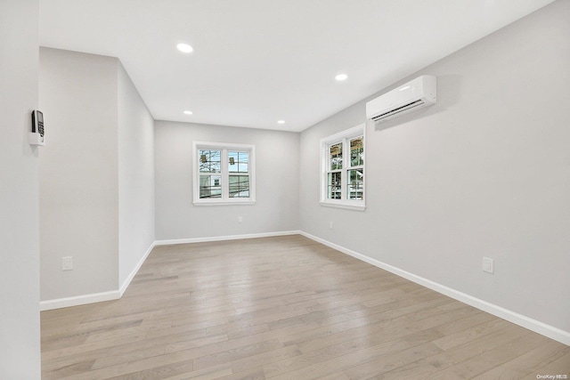 empty room with light wood-type flooring and an AC wall unit