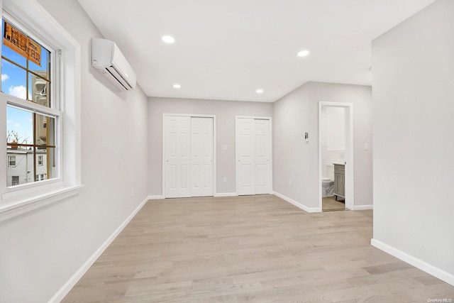 spare room featuring an AC wall unit, a fireplace, and light wood-type flooring