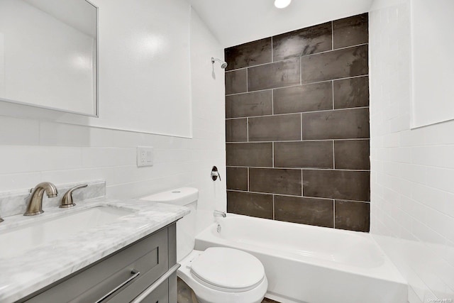 full bathroom with toilet, vanity, tile walls, and tiled shower / bath