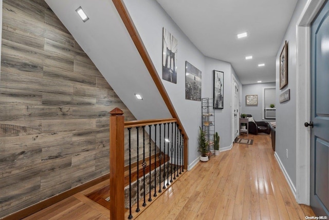 hallway featuring light wood-type flooring and wood walls