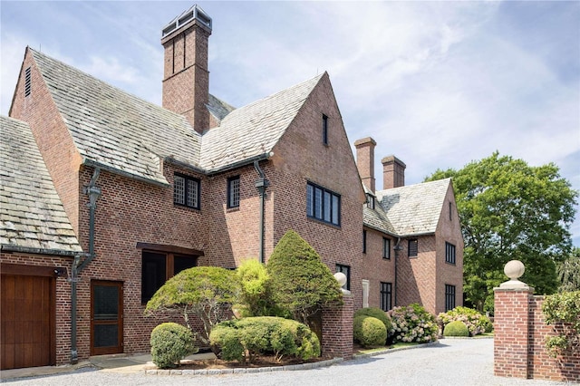 16 Tuthill Ln, Remsenburg, NY 11960 - view of side of home with a high end roof, a chimney, and brick siding