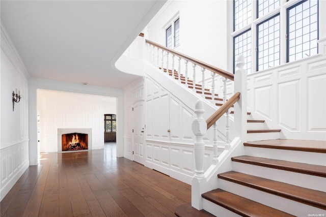 stairs with hardwood / wood-style floors, a towering ceiling, and crown molding