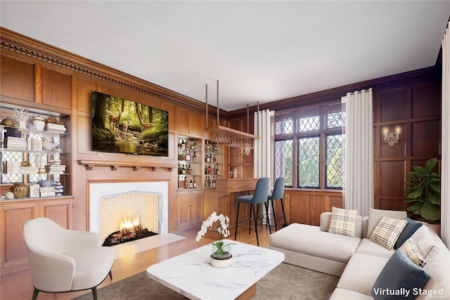 living room featuring built in shelves, wooden walls, light hardwood / wood-style floors, and ornamental molding