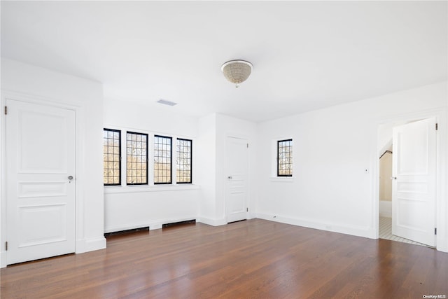 spare room with dark hardwood / wood-style flooring and plenty of natural light