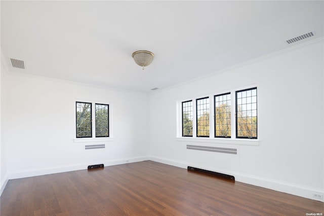 spare room with dark wood-type flooring, crown molding, and a healthy amount of sunlight