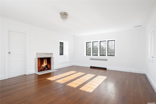 unfurnished living room with radiator heating unit, ornamental molding, and dark wood-type flooring