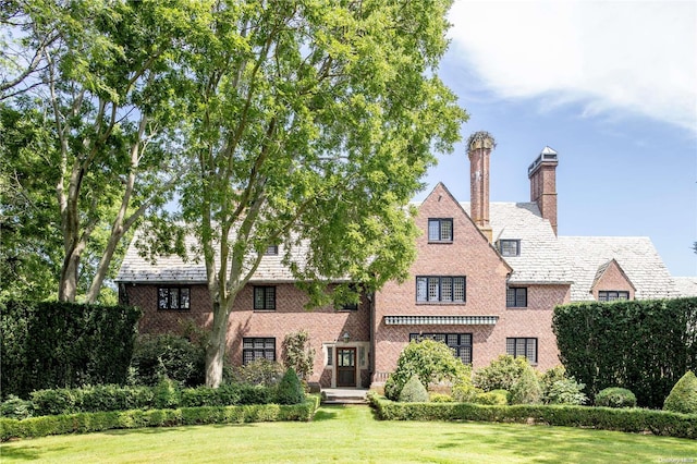16 Tuthill Ln, Remsenburg, NY 11960 - tudor-style house with a front lawn, brick siding, a chimney, and a high end roof