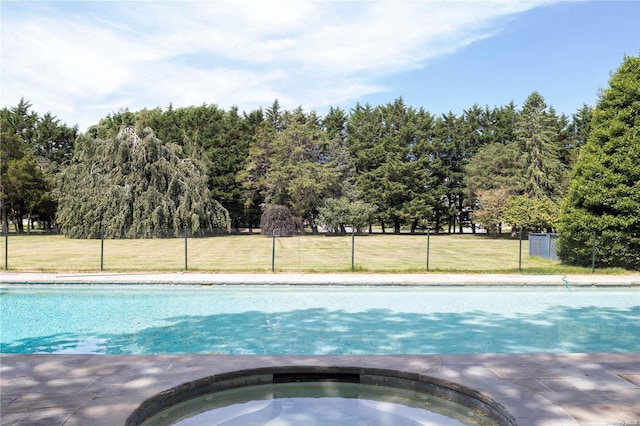 view of swimming pool with a lawn and an in ground hot tub