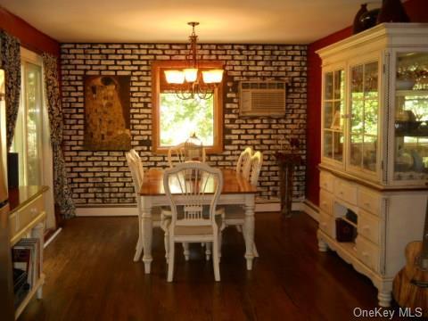 dining space featuring dark hardwood / wood-style floors, an inviting chandelier, and brick wall