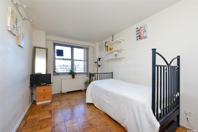 bedroom featuring radiator heating unit and parquet floors