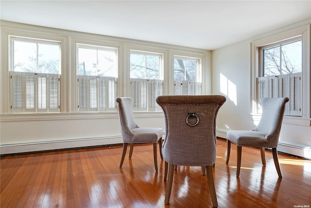 dining space with hardwood / wood-style flooring and a baseboard heating unit