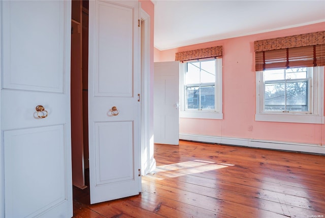 spare room featuring wood-type flooring, a baseboard radiator, and a wealth of natural light