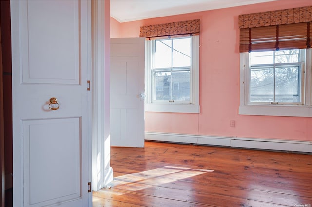 spare room with plenty of natural light, crown molding, light wood-type flooring, and baseboard heating