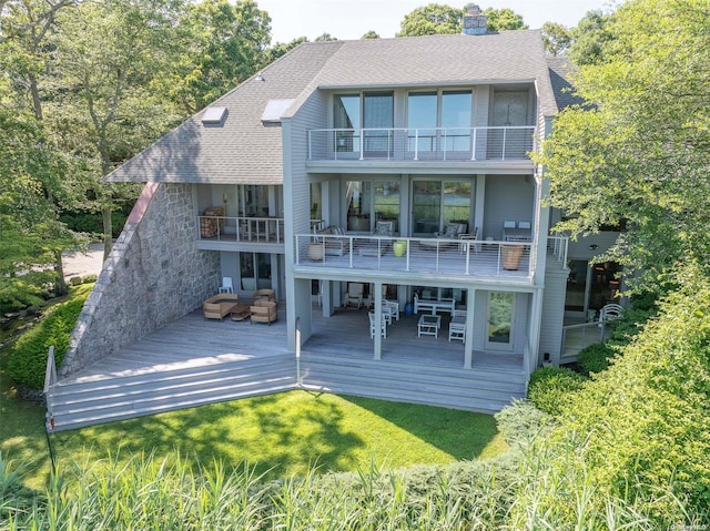 rear view of property featuring an outdoor living space, a balcony, and a lawn