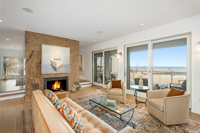 living room with a high end fireplace, a water view, and hardwood / wood-style flooring