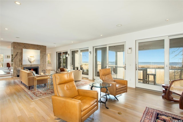 living room featuring a fireplace, light hardwood / wood-style floors, and a water view