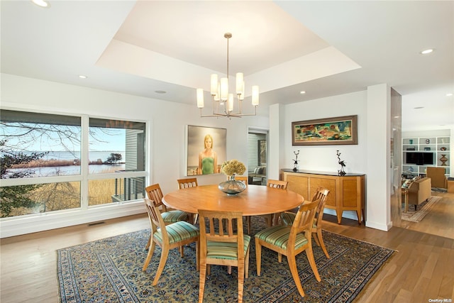 dining room with hardwood / wood-style floors, a tray ceiling, and a chandelier