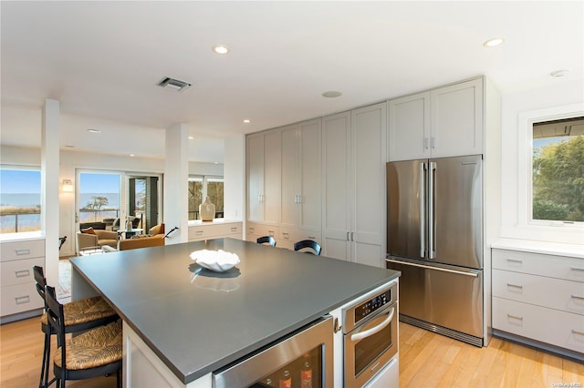 kitchen featuring appliances with stainless steel finishes, a center island, light hardwood / wood-style floors, and a breakfast bar area