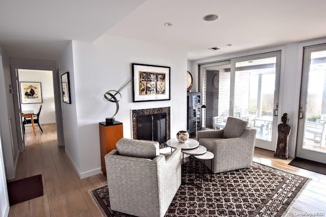 living room with a high end fireplace and hardwood / wood-style flooring