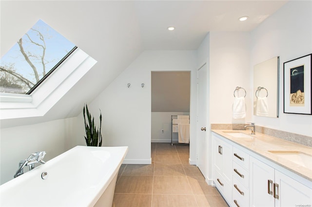 bathroom with a washtub, vanity, tile patterned flooring, and lofted ceiling with skylight