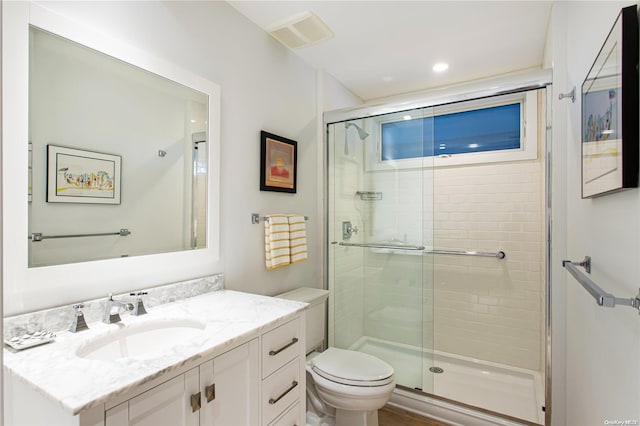 bathroom featuring vanity, toilet, and a shower with door