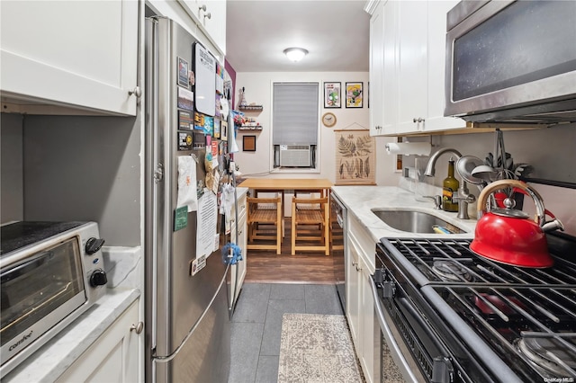 kitchen with white cabinets, appliances with stainless steel finishes, dark hardwood / wood-style floors, and sink