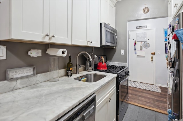 kitchen featuring white cabinetry, sink, light stone countertops, dark hardwood / wood-style floors, and appliances with stainless steel finishes