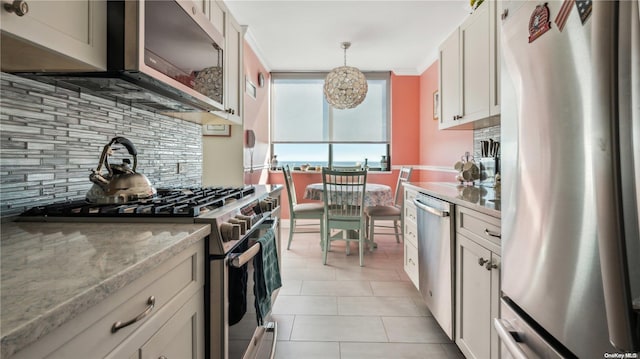 kitchen featuring decorative backsplash, light stone countertops, stainless steel appliances, white cabinetry, and hanging light fixtures