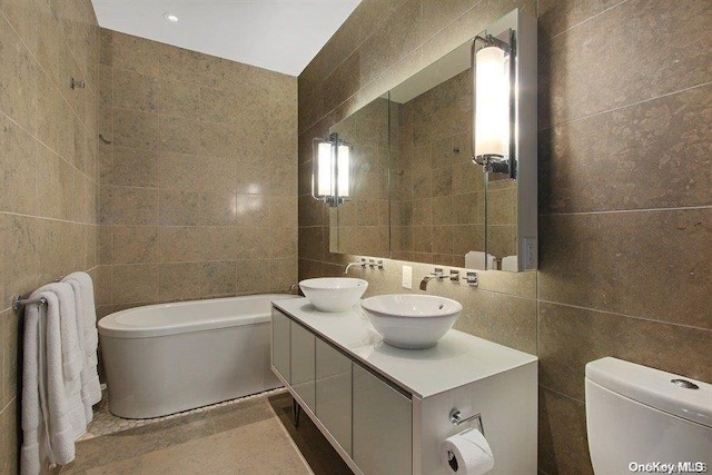 bathroom with vanity, a bathing tub, toilet, tile walls, and tasteful backsplash