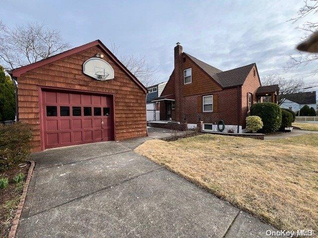 view of front facade with a front yard, a garage, and an outdoor structure