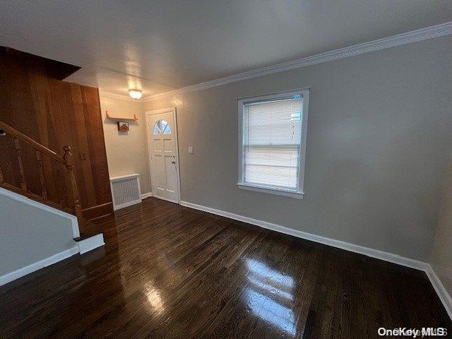 foyer featuring crown molding and dark wood-type flooring