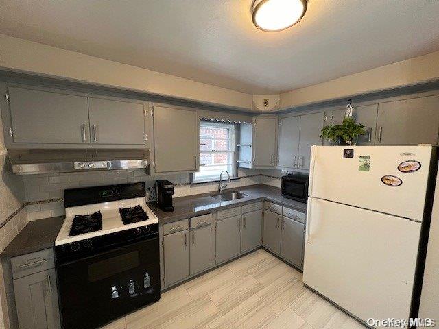 kitchen featuring tasteful backsplash, gray cabinetry, sink, and black appliances